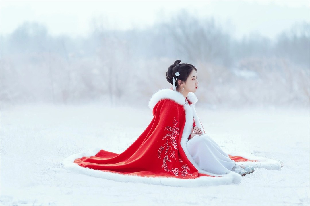 雪地红斗篷少女撑白伞，花簪垂珠与毛绒镶边清冷出镜