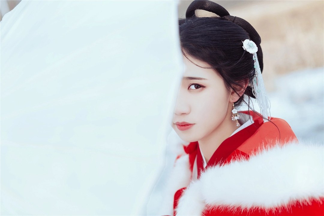雪地红斗篷少女撑白伞，花簪垂珠与毛绒镶边清冷出镜