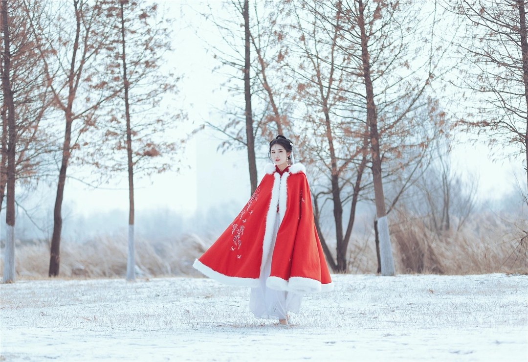 雪地红斗篷少女撑白伞，花簪垂珠与毛绒镶边清冷出镜