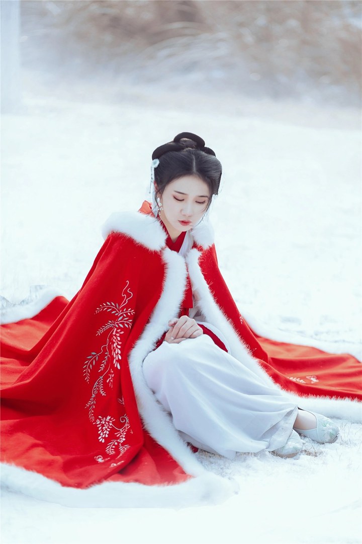 雪地红斗篷少女撑白伞，花簪垂珠与毛绒镶边清冷出镜