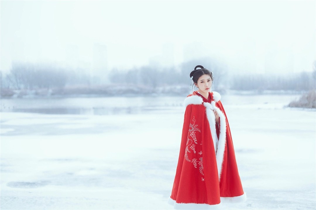 雪地红斗篷少女撑白伞，花簪垂珠与毛绒镶边清冷出镜