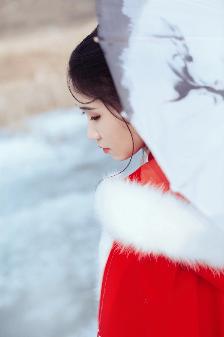 雪地红斗篷少女撑白伞，花簪垂珠与毛绒镶边清冷出镜